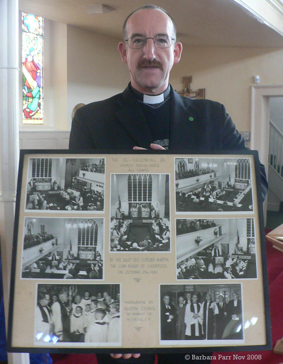 Revd. John Taylor holding photos of the Re-Hallowing of All Saints by the Bishop of Liverpool on 25 Oct 1961