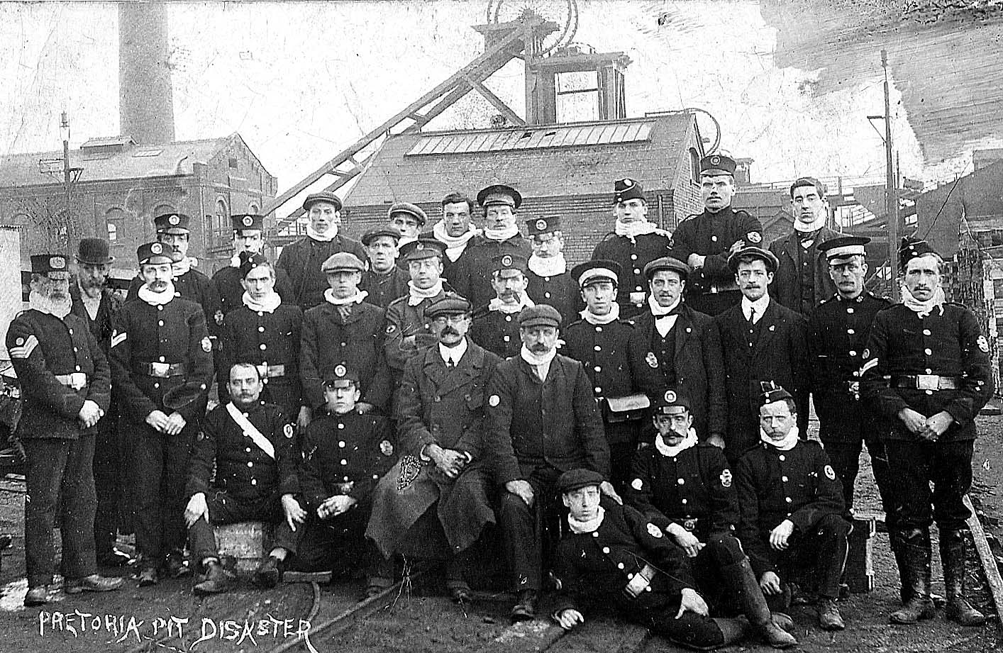 Dr Hatton (centre) and men of Westhoughton Ambulance
Brigade in front of the No.3 shaft headgear and engine house. Note the
white mufflers many are wearing - most probably to soak with eucalyptus oil
and pull over the face when dealing with the decomposing bodies in the
mortuary. Photo supplied by Maxine