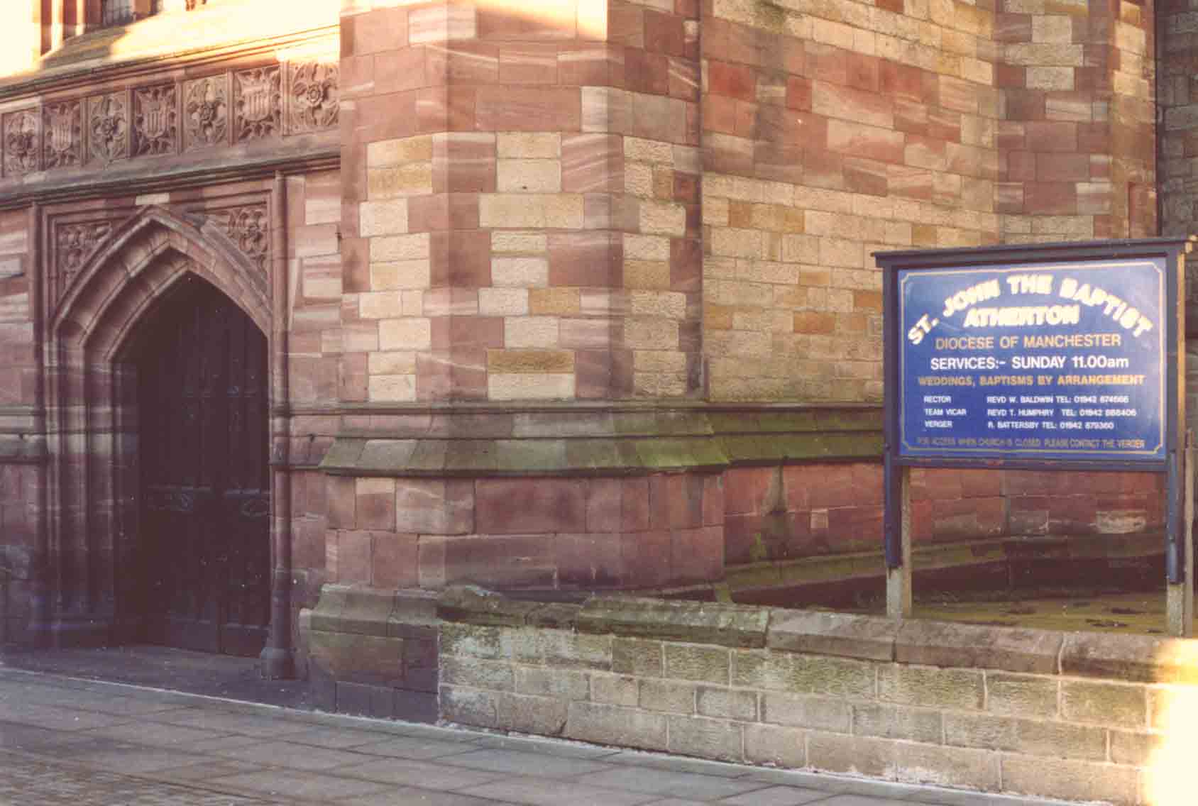St John the Baptist, Atherton, porch at the base of the tower. Note the contrast between the mellow red Cheshire masonry of the tower, and the dull brown local sandstone of the wall. Photo by Peter wood 22 Dec 2003